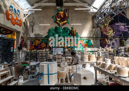 Ateliers Arquié Kunstporzellanwerkstatt in Limoges. Die Werkstatt verbindet traditionelle Handwerkskunst mit modernen Formen, Farben und Techniken. Das Atelier befindet sich in ehemaligen Spinnerei- und Webgebäuden am Ufer der Vienne, an den Wänden sind großformatige Graffiti-Werke regionaler Künstler zu sehen. Avenue Baudin, Limoges, Nouvelle-Aquitaine, Frankreich Stockfoto