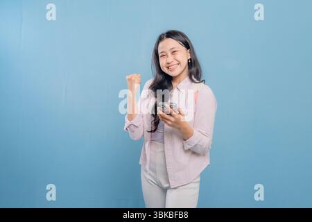 Eine Frau hält ein Handy und lächelt. Sie ist glücklich und aufgeregt. Vorstellung von Freude und Positivität Stockfoto