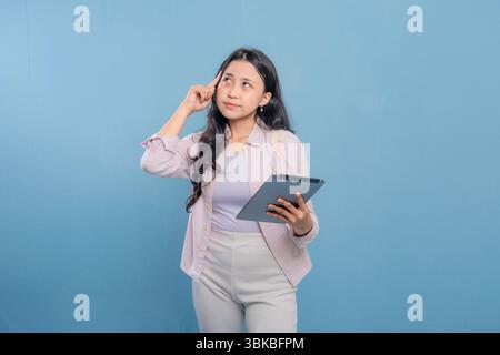Eine Frau hält eine Tafel und blickt an die Decke. Sie ist tief in Gedanken Stockfoto