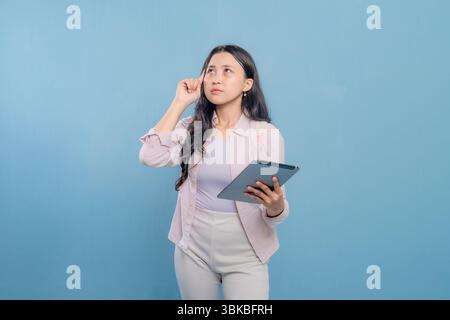 Eine Frau hält eine Tafel und blickt an die Decke. Sie ist tief in Gedanken Stockfoto