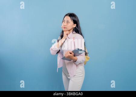Eine Frau hält eine Tafel und blickt an die Decke. Sie ist tief in Gedanken Stockfoto