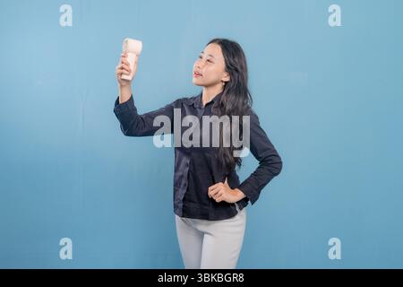 Eine Frau hält einen Miniventilator in der Hand. Sie lächelt und ist glücklich Stockfoto