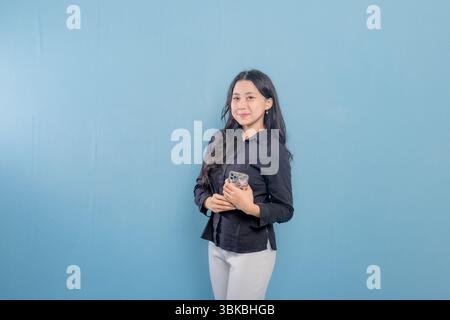 Eine Frau hält ein Handy. Sie lächelt und ist glücklich. Konzept moderner Technik und Kommunikation Stockfoto
