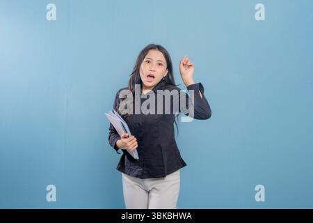 Eine Frau hält ein Buch und lächelt. Sie ist glücklich und aufgeregt. Vorstellung von Freude und Begeisterung Stockfoto