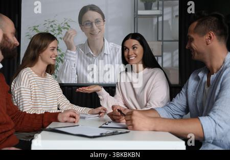 Gruppe von Personen, die an einer Geschäftskonferenz im Innenbereich teilnehmen. Lautsprecher auf Projektionsleinwand Stockfoto