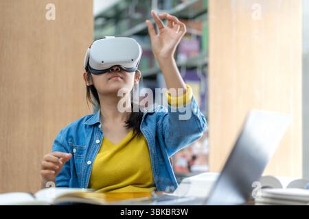 Eine junge Frau, die ein VR-Headset trägt, interagiert während des Studiums in einer Bibliothek mit virtuellen Inhalten und symbolisiert moderne Bildung und immersive Technologie. Stockfoto