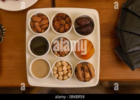 Ein Holztisch für das Hotelfrühstück mit kleinen Tellern mit verschiedenen Nüssen und getrockneten Früchten, die von oben erfasst wurden. Stockfoto