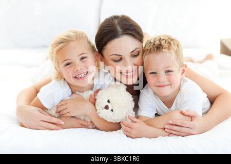 Fröhliche Kinder mit ihrer Mutter auf einem Bett liegend Stockfoto