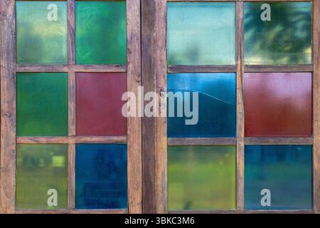 Das Fenster besteht aus Buntglas und hat ein farbenfrohes Design. Die Farben sind blau, rot und grün Stockfoto