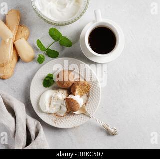 Tiramisu-Bällchen mit Schlagsahne auf der weißen Platte mit Kaffee in der Nähe. Draufsicht, Kopierraum Stockfoto