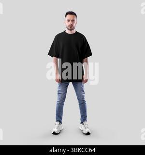 Modell eines schwarzen Oversize-T-Shirts auf bärtigen Mann in Jeans, Sneakers, durchgehende Vorderansicht, isoliert auf Hintergrund. Modische Hemdschablone für Design Stockfoto