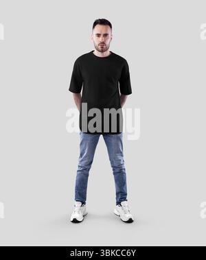 Modell eines schwarzen Oversize-T-Shirts auf bärtigem Mann in Jeans, Turnschuhen, durchgehende Vorderansicht, isoliert auf Hintergrund. Produktfotografie für Werbung Stockfoto