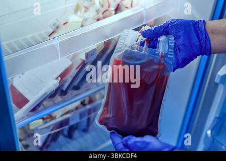 Arzt hält einen Beutel rotes Blut im Blutlagerungskühlschrank im Labor der Blutbank-Abteilung im Krankenhaus. Lebensrettend und tr Stockfoto