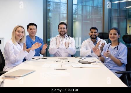 Eine vielfältige Gruppe von Medizinern applaudiert während eines Meetings und vermittelt Teamarbeit und Erfolg. Stockfoto