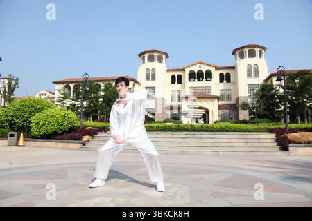 Ein junger Mann, der in traditioneller chinesischer Tai-Chi-Kleidung praktiziert Stockfoto