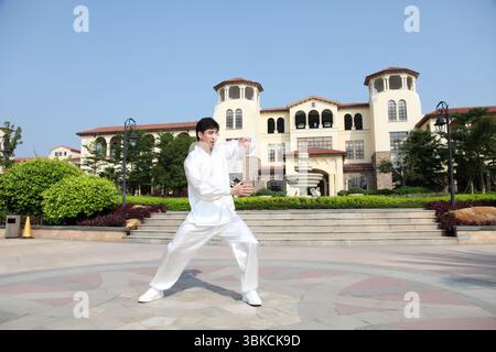Ein junger Mann, der in traditioneller chinesischer Tai-Chi-Kleidung praktiziert Stockfoto