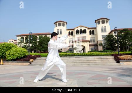 Ein junger Mann, der in traditioneller chinesischer Tai-Chi-Kleidung praktiziert Stockfoto
