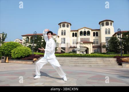 Ein junger Mann, der in traditioneller chinesischer Tai-Chi-Kleidung praktiziert Stockfoto