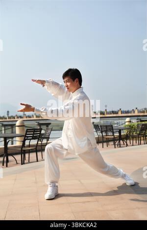 Ein junger Mann, der in traditioneller chinesischer Tai-Chi-Kleidung praktiziert Stockfoto