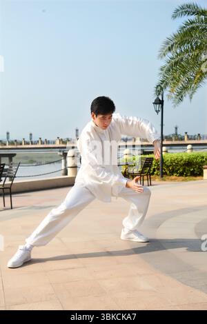 Ein junger Mann, der in traditioneller chinesischer Tai-Chi-Kleidung praktiziert Stockfoto