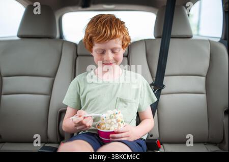 Glückliches Kind mit Eisbecher im Fahrzeug Stockfoto