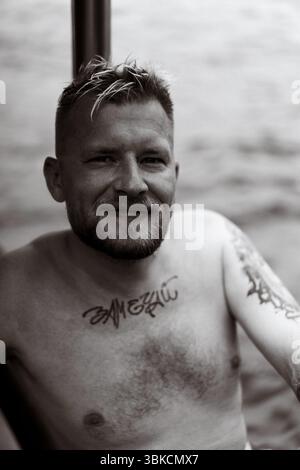 Tätowierter Mann, der auf dem Boot ruht, im monochromen Porträt, Nusa Penida Stockfoto