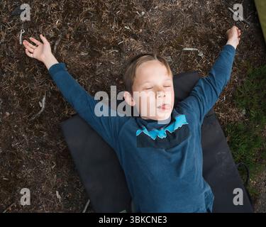 Junge, der müde auf einem Crash-Matt liegt, nachdem er draußen geklettert ist Stockfoto
