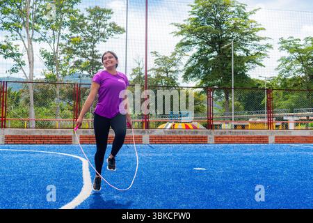 Latina Woman springt mit Dynamic Arch auf dem Outdoor Court Stockfoto