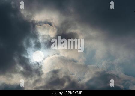 Vollmond bei dramatisch bewölktem Himmel. Erschreckend dunkle Sicht auf den Nachthimmel. Stockfoto