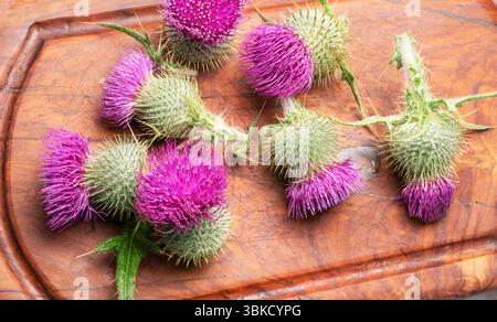 Mariendistel Blumenköpfe auf hölzernem Schneidebrett. Draufsicht. Stockfoto