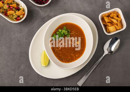 Scharfe mexikanische Hühnersuppe mit Nudeln, garniert mit frischem Koriander und Limettenkeil Stockfoto