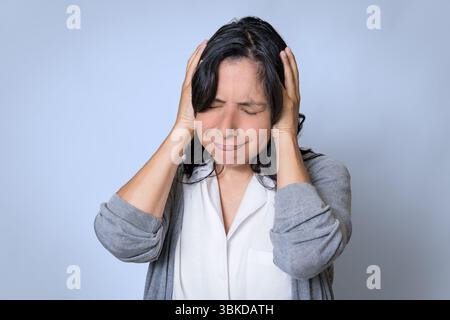 Junge Erwachsene hispanische Frau in ihren 40ern mit Kopfschmerzen, Porträt der besorgten und traurigen Frau mit psychischen Problemen Stockfoto