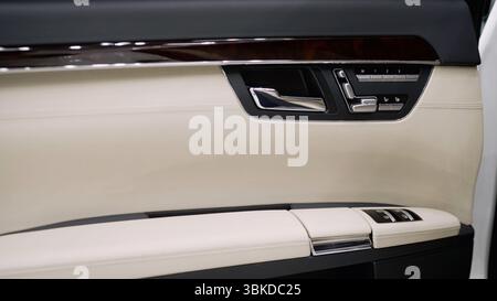 Tür von innen in weißem Leder, ein teures ausländisches Auto. Innenraum der Autotür. Autotür von innen. Innenraum des Fahrzeugs. Stockfoto