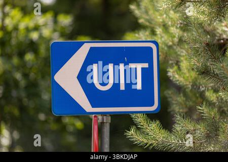 Holländische Straße und Verkehrsschild mit Pfeil und dem Wort Exit, das in Richtung der Richtung zeigt, auf dem Autos auf einem Parkplatz folgen können Stockfoto