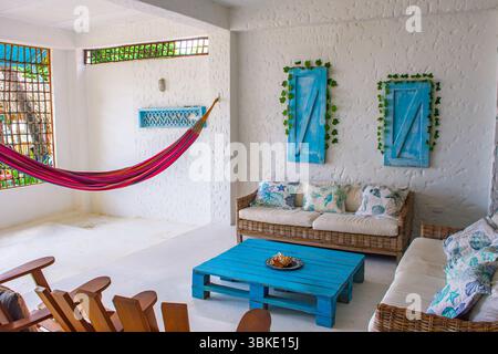 Heller und einladender Wohnbereich an der Küste mit farbenfroher Hängematte, Korbmöbeln und stilvollem Dekor, perfekt zum Entspannen in Rincon del Mar. Stockfoto