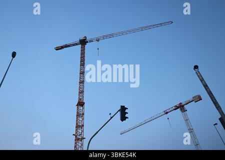 Turmkräne bei Sonnenuntergang auf einer Baustelle symbolisieren Wachstum und Entwicklung. Stockfoto