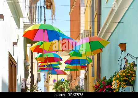 Olbia, Sardinien, Italien - 14. Juni 2025: Bunte Regenschirme schmücken eine enge Gasse in Olbia auf Sardinien und sorgen für sommerliche Farbenpracht *** Bunte Regenschirme schmücken eine enge Gasse in Olbia auf Sardinien und sorgen für sommerliche Farbenpracht Stockfoto