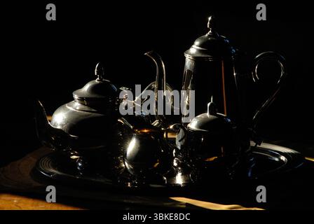 Elegantes Stillleben eines antiken Silberteesets, dramatisch beleuchtet im Hell-Dunkel-Stil Stockfoto