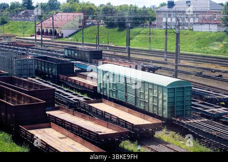 Ein belebter Bahnhofshof, der mit zahlreichen Zugwagen unterschiedlicher Größe und Form gefüllt ist, darunter ein auffällig hellgrüner Zug Stockfoto
