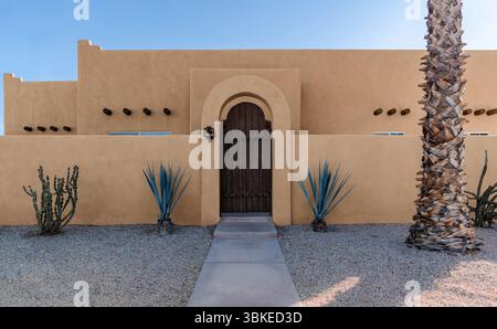 Adobe Southwest Pueblo-Architektur in der amerikanischen Wüste mit Kakteen und einer Palme Stockfoto