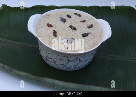 Köstlicher südindischer Reis Payasam mit Zierfleisch, Milch, garniert mit Rosinen, serviert in einer Keramikschale auf einem Bananenblatt. Stockfoto