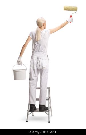Eine Hausmalerin malt eine Wand auf einer Leiter Stockfoto