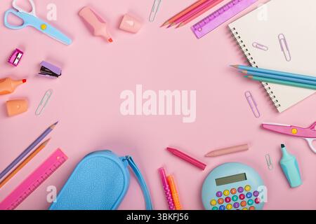 Rahmen mit Schulutensilien, Notizblock, Taschenrechner und Schere auf rosa Hintergrund. Back-to-School-Konzept. Stockfoto