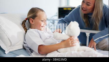 Teddybär, spielend und Mutter mit Kind im Krankenhaus mit Besuch für Unterstützung, Bindung oder Erholung. Lächeln, flauschiges Spielzeug und Mama, die Spaß mit Mädchen hat Stockfoto