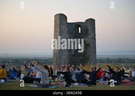 Hadleigh Essex, Großbritannien. Juni 2025. Ein Yoga-Kurs begrüßt The Dawn bei Sonnenaufgängen an der Sommersonnenwende im Hadleigh Castle in Essex, Großbritannien. Die aktuelle Hitzewelle wird voraussichtlich heute (21. Juni 25) ihren Höhepunkt erreichen, wobei die Temperaturen voraussichtlich 34 °C erreichen werden Quelle: MARTIN DALTON/Alamy Live News Stockfoto