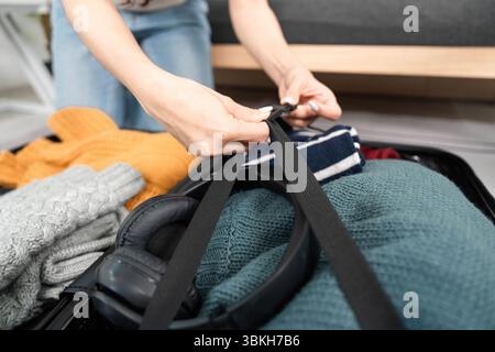 Verpackung für Reisen. Eine Person, die Kleidung und Accessoires in einem Koffer organisiert. Stockfoto