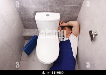Professioneller Klempner, der die Toilettenschüssel in der Toilette befestigt, über dem Blick Stockfoto