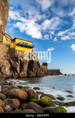 Gebäude über dem steinigen Strand in Ponta do Sol, Insel Madeira, Portugal, am Abend Stockfoto