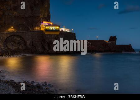 Gebäude über dem steinigen Strand in Ponta do Sol, Insel Madeira, Portugal, nachts Stockfoto
