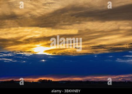 Ein lebhafter Sonnenuntergang mit gelben, blauen und roten Farbtönen über den Himmel, der einen atemberaubenden natürlichen Verlauf erzeugt. Stockfoto